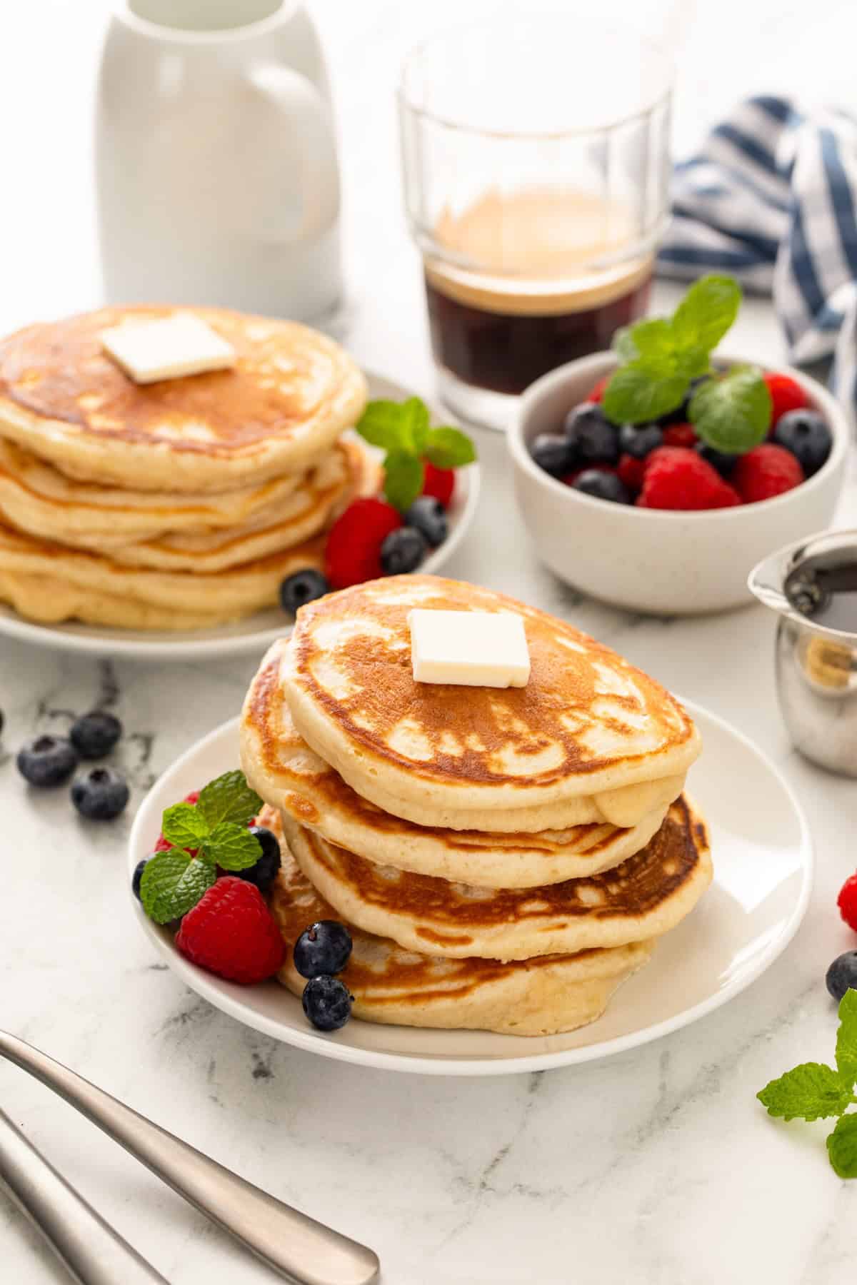 Several plates are topped with stacks of homemade pancakes.