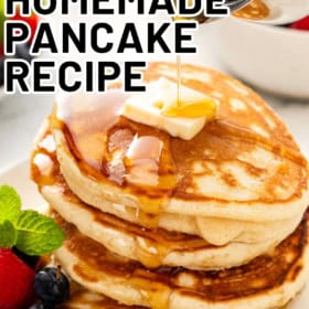 Easy fluffy homemade pancakes presented on a white plate with berries, butter, and syrup.