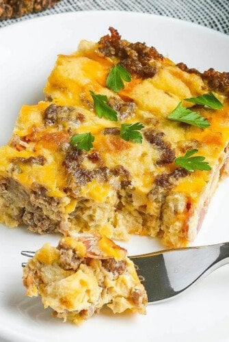 Up close image of overnight breakfast casserole on plate with a fork taking a bite of it.