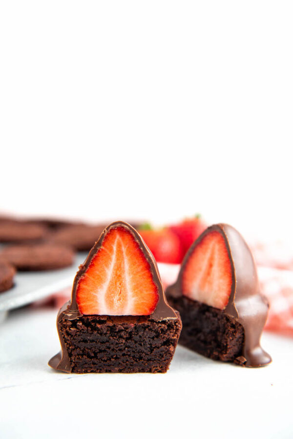 Chocolate Covered Strawberry Brownie Bites cut in half with brownie bites behind them.