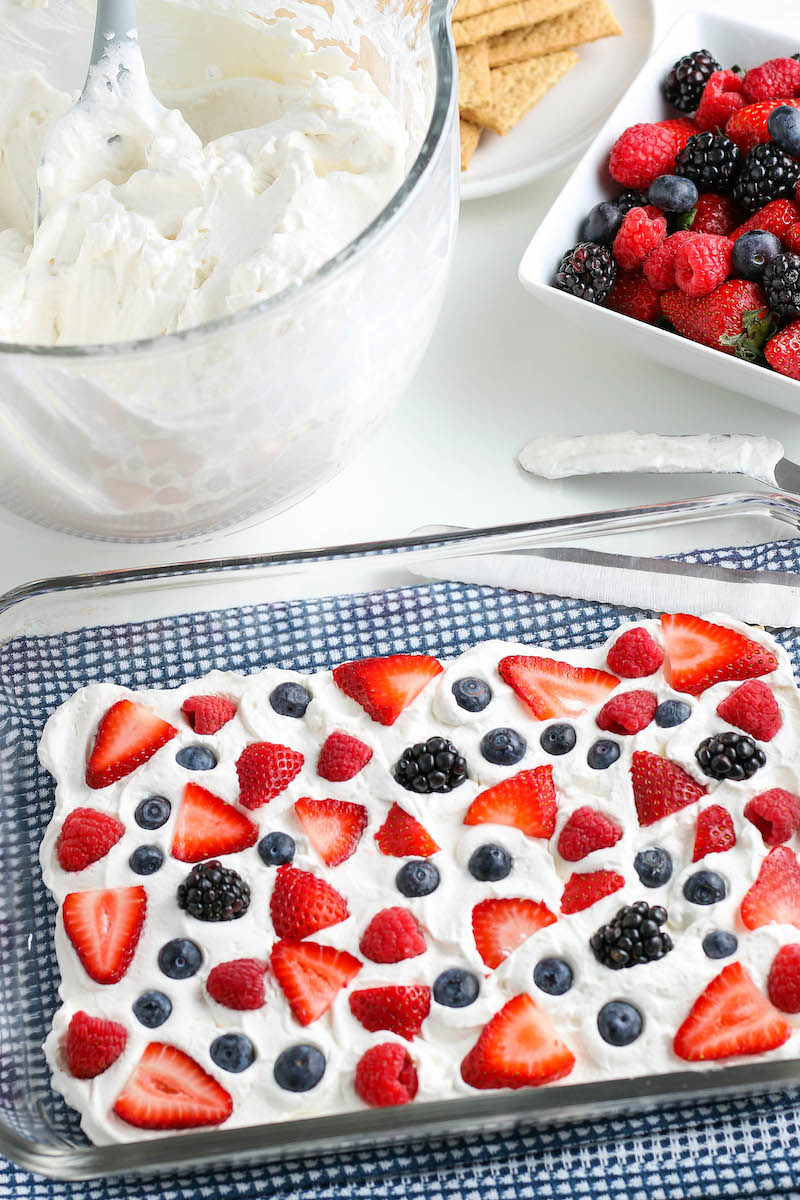 Pan with a layer of whipped cream with blueberries and strawberries on top.