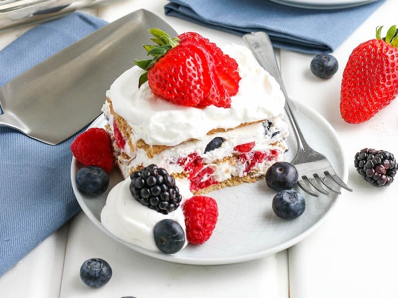 A square of icebox confection with whipped surf and berries on a plate