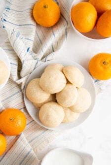 whipped shortbread cookies on a plate with oranges and a napkin besides them.