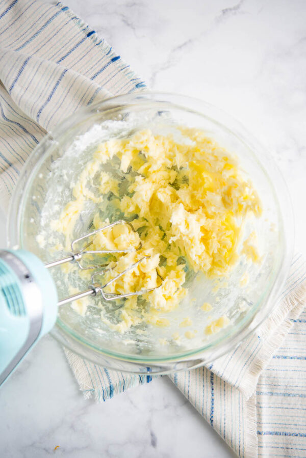 Butter and powdered sugar beaten together in a glass bowl with a tea towel.