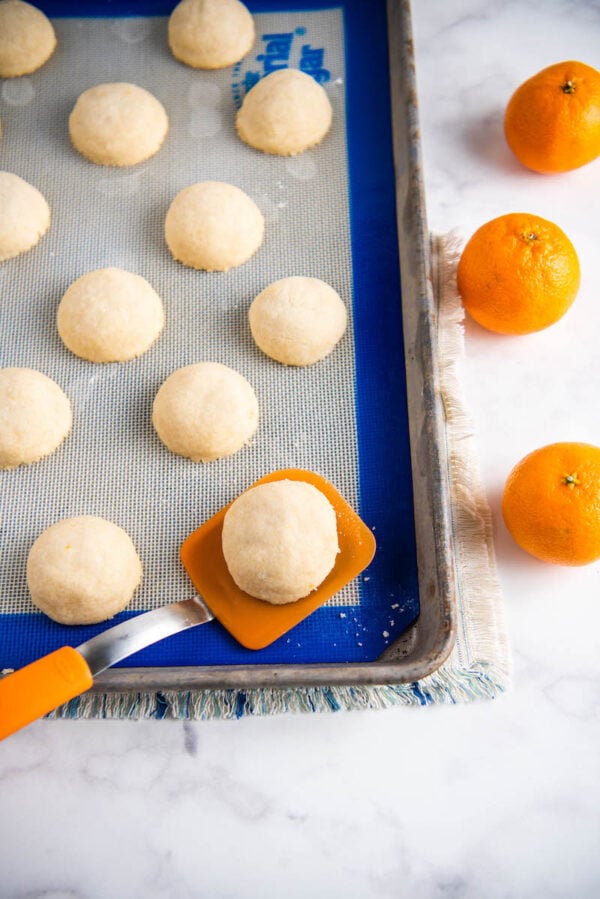 Orange shortbread cookies on a cookie sheet with a spatula.