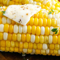 Up close image of grilled corn with butter and herbs.
