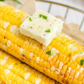 Up close image of corn on the cob in a basket with parchment paper.