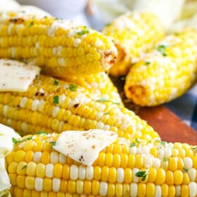 Stacked corn cobs with seasoning and butter.