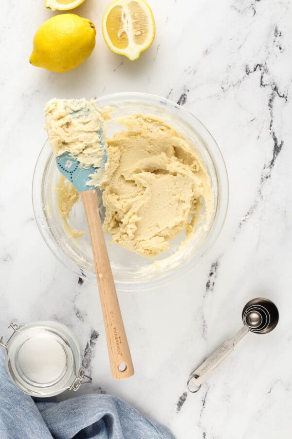 Dough for whipped shortbreads with a spatula and lemons.