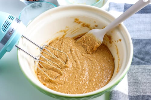 A bowl of the peanut butter mixture with a whisk and spatula in it.