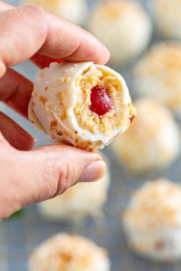 A hand holding a no bake truffle with a bite taken out of it.