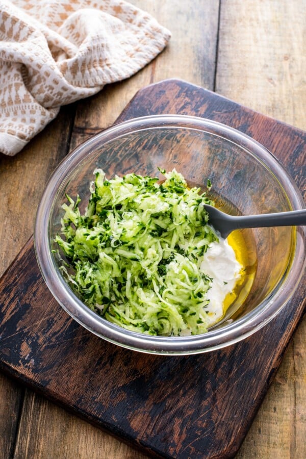 Grated cucumber in a bowl with Greek yogurt and olive oil.