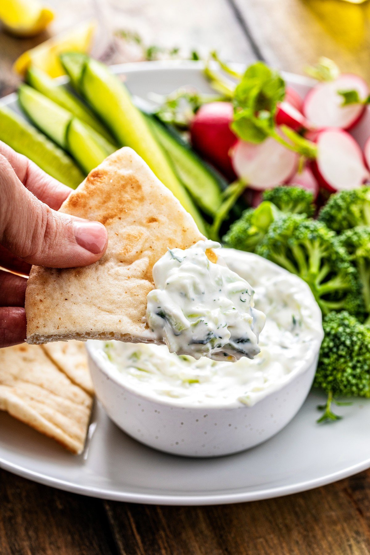 A slice of pita bread with some tzatziki on it.