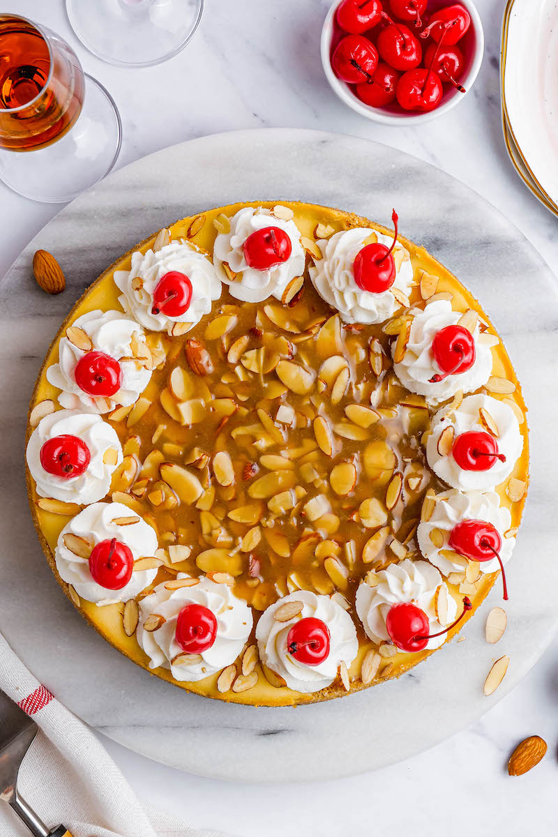 Almond amaretto cheesecake with toasted almonds, whipped cream, and cherries on top.