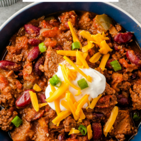 Chunky chili in a blue bowl with toppings on top and wording on top of the image.