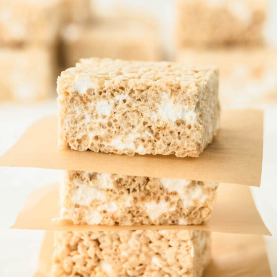 Stacked rice krispie treats with parchment paper in between them.
