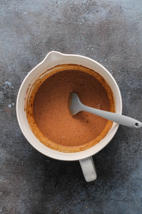 A white bowl with pancake batter in it with a spatula inside stirring.