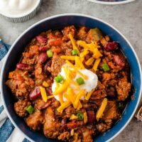Bowl of chunky chili with cheese sprinkled on top.