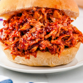 Pinterest image of bbq chicken on a sandwich roll on a white plate with lettering on the bottom.