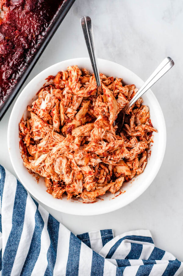 Pulled chicken in a bowl with two forks.