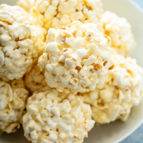 A plate is holding a pile of marshmallow popcorn balls