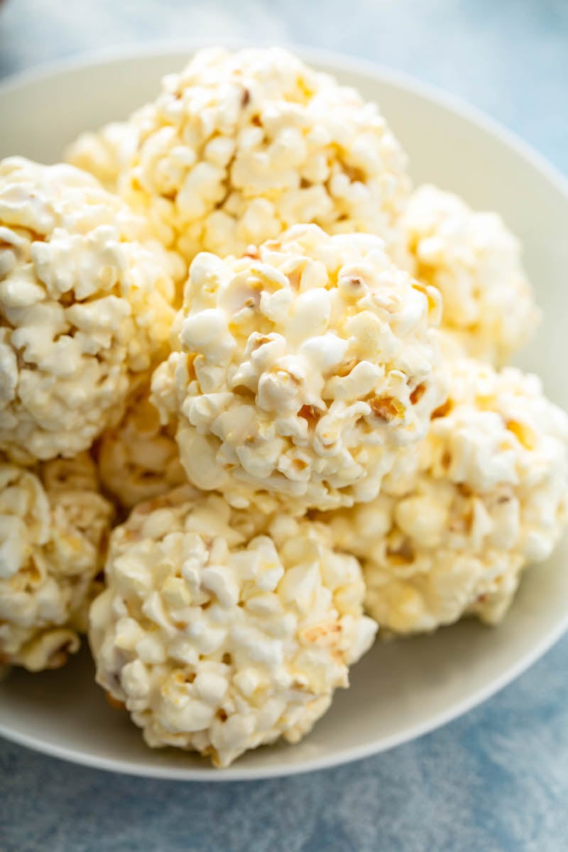 A plate is holding a pile of marshmallow popcorn balls