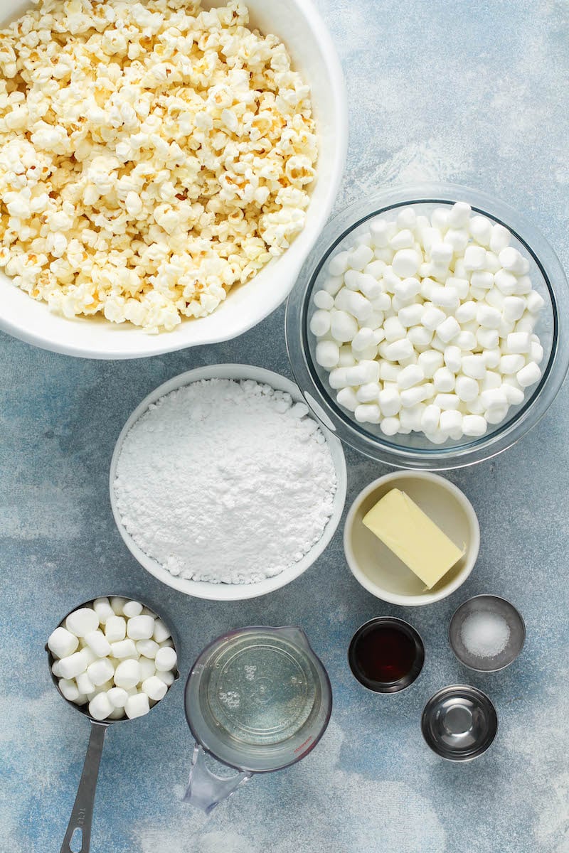 The ingredients for marshmallow popcorn treats are placed on a white tabletop
