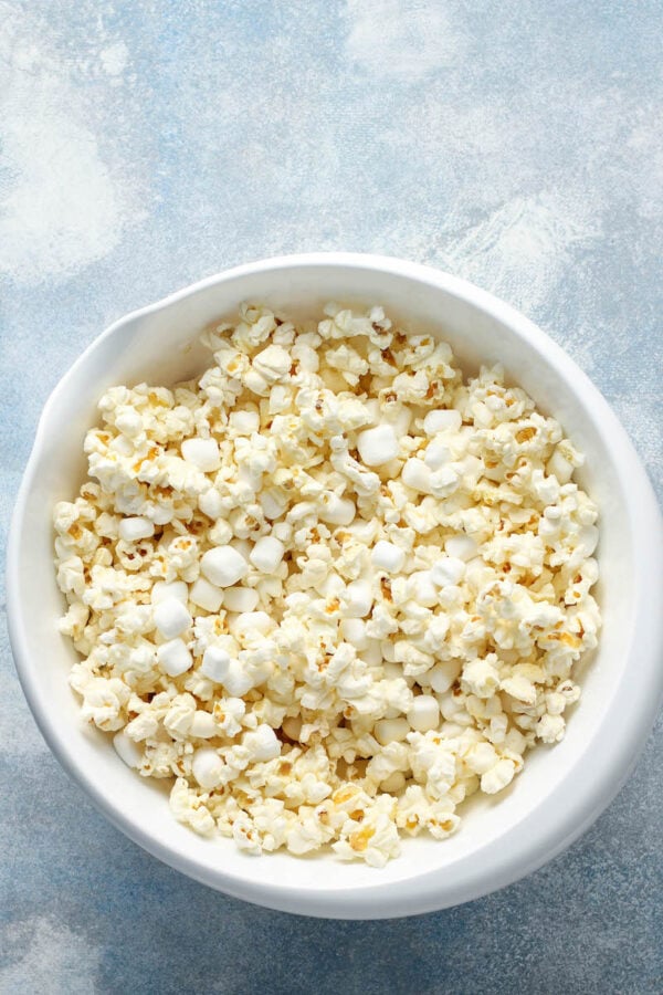 A bowl of popped popcorn is sitting on a white tabletop