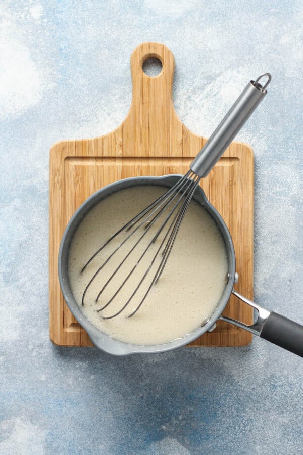 Melted marshmallows are being whisked in a silver pot