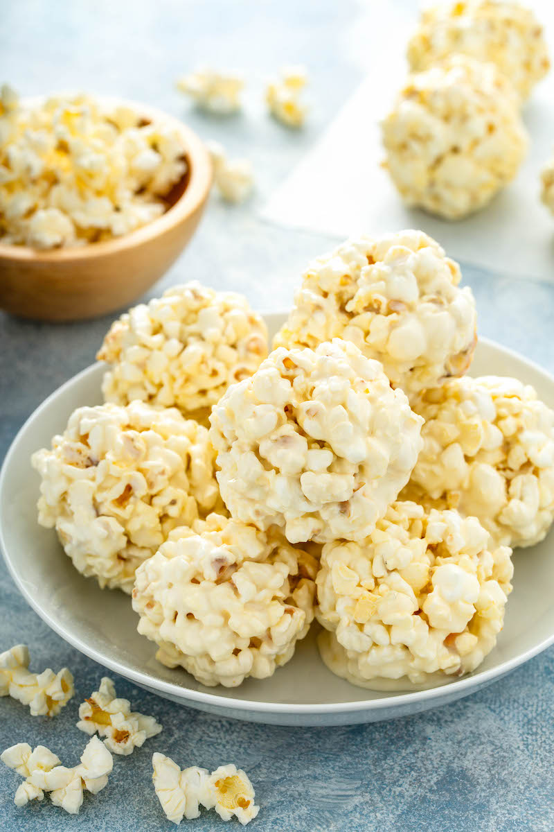 A pile of marshmallow popcorn balls is on a white plate