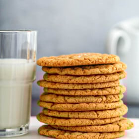 Stack of molasses cookies next to a glass of milk.