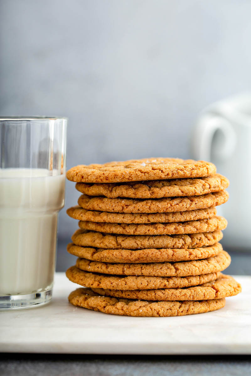 Stack of molasses cookies next to a glass of milk.