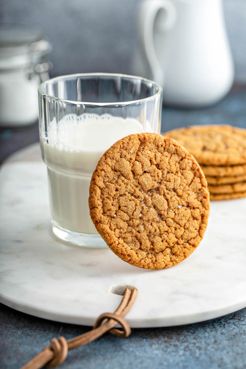 Molasses cookie leaning against a glass of milk.