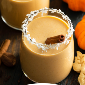 Pumpkin Coquito in two glasses with cinnamon sticks and wording on the bottom.