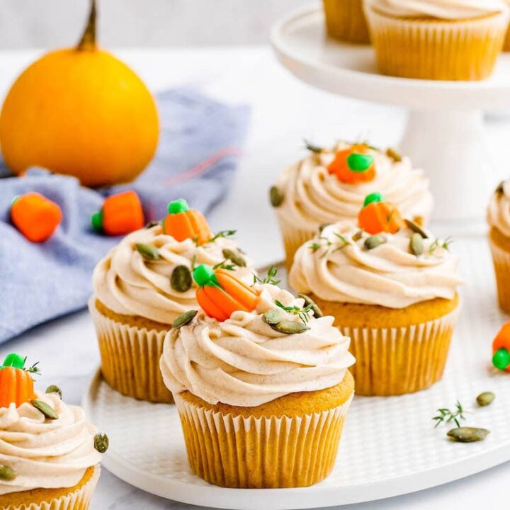 Pumpkin cupcakes with frosting and candy pumpkins on top.