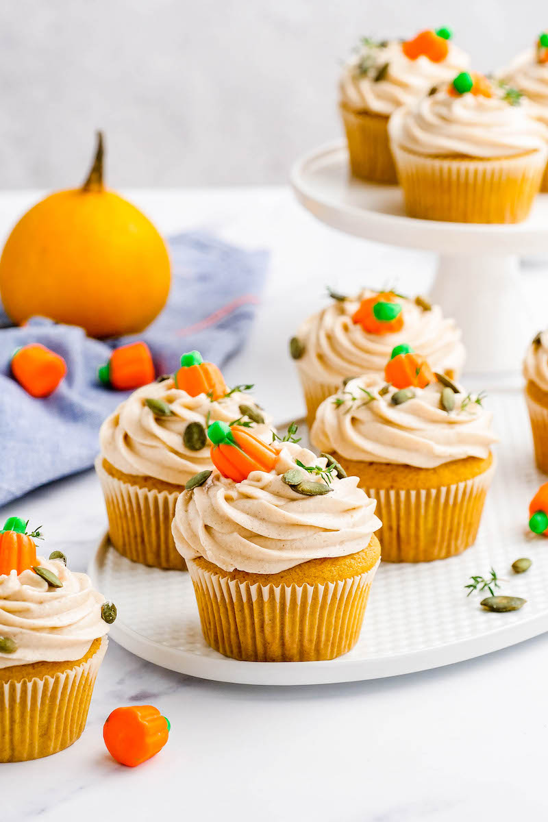 Pumpkin cupcakes with frosting and candy pumpkins on top.