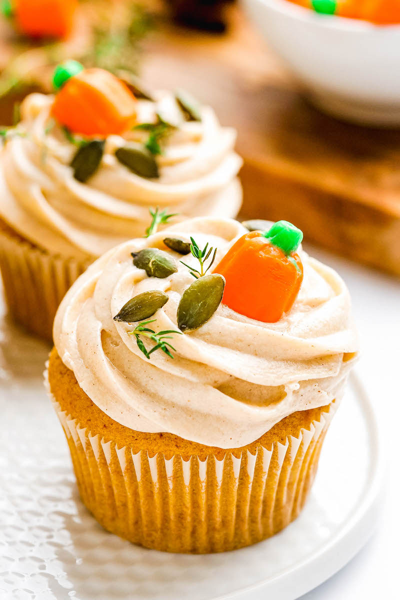 Pumpkin cupcakes with frosting and fall decorations on top.