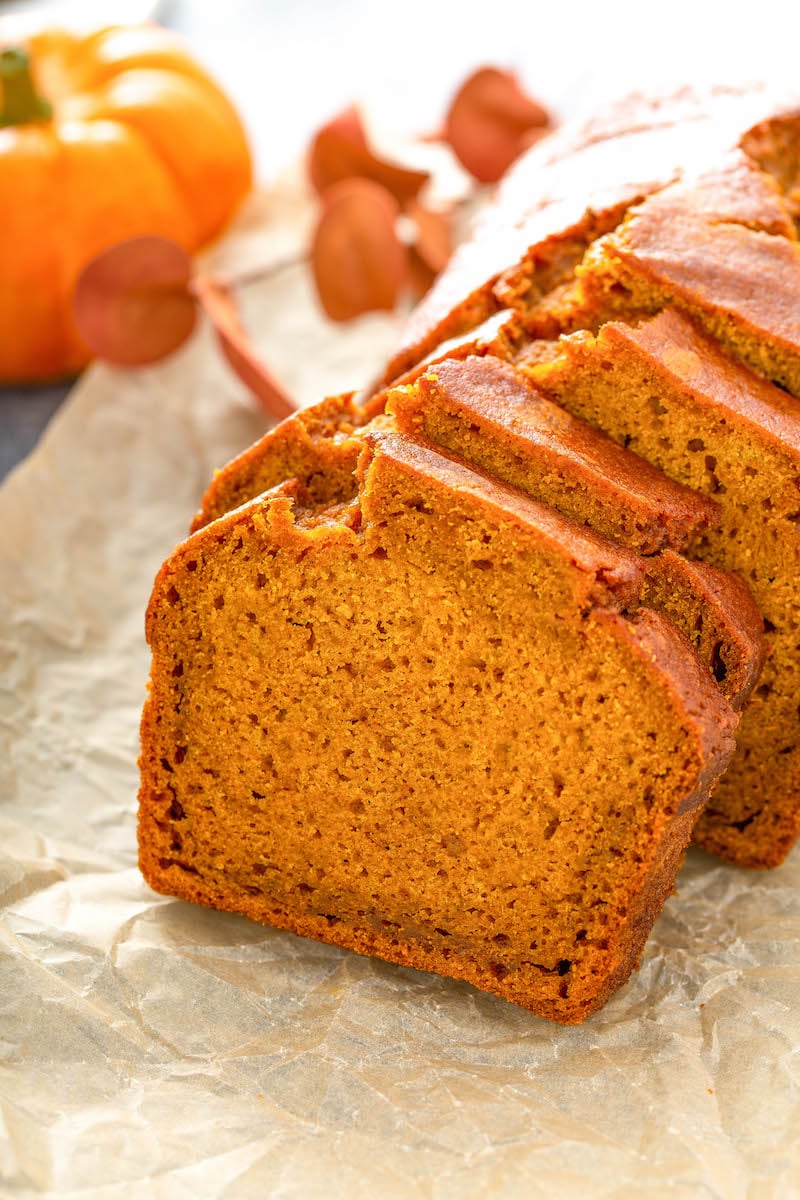 Pumpkin bread sliced and stacked against each other on parchment paper. 