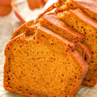 Up close image of pumpkin bread sliced on a piece of parchment paper.
