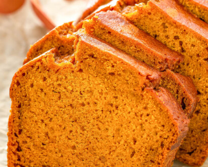 Up close image of pumpkin bread sliced on a piece of parchment paper.