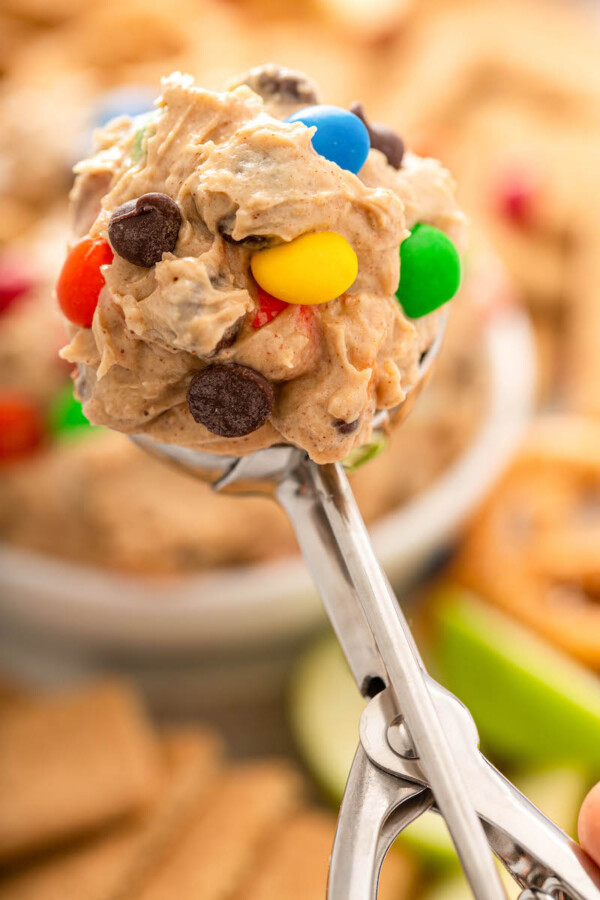 A spoonful of cookie dough dip is held above a bowl