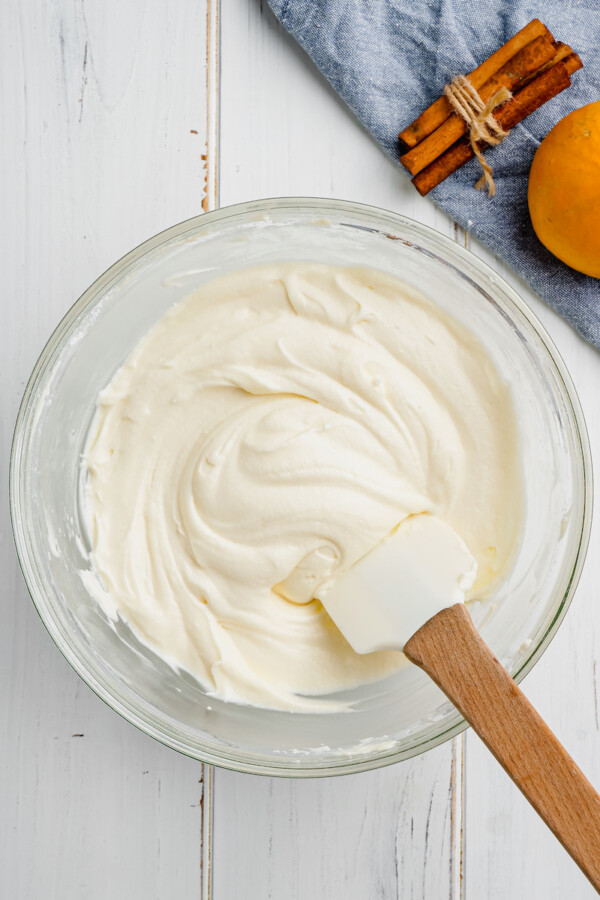 White cream cheese icing is mixed in a glass bowl