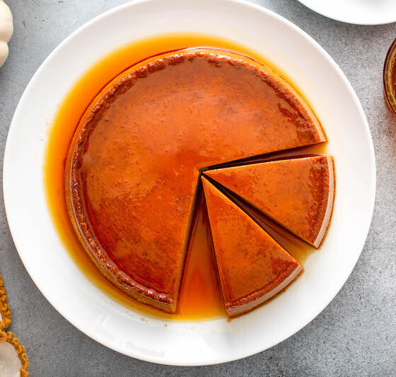 Two slices of pumpkin flan are being sliced out of the dessert
