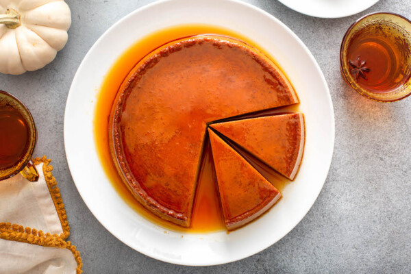 Two slices of pumpkin flan are being sliced out of the dessert