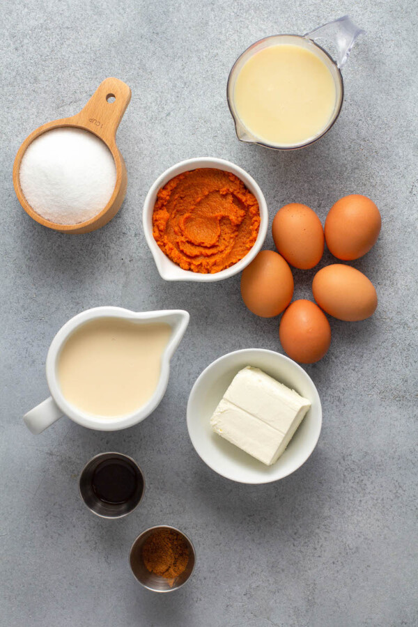 The ingredients for pumpkin flan are spread out on a gray surface