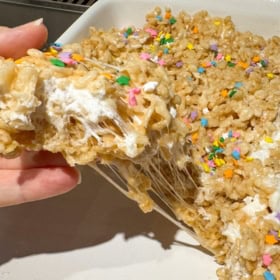 A hand pulling a homemade Rice Krispies treat from a pan.