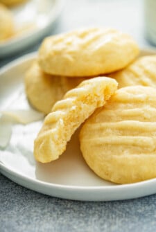 A few coconut cookies are stacked on a white plate.