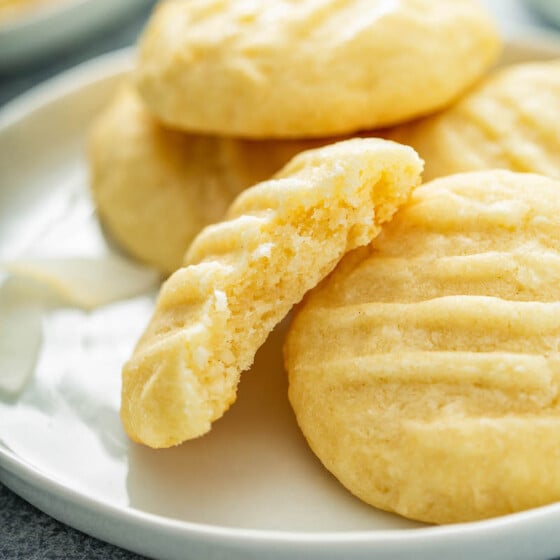 A few coconut cookies are stacked on a white plate.
