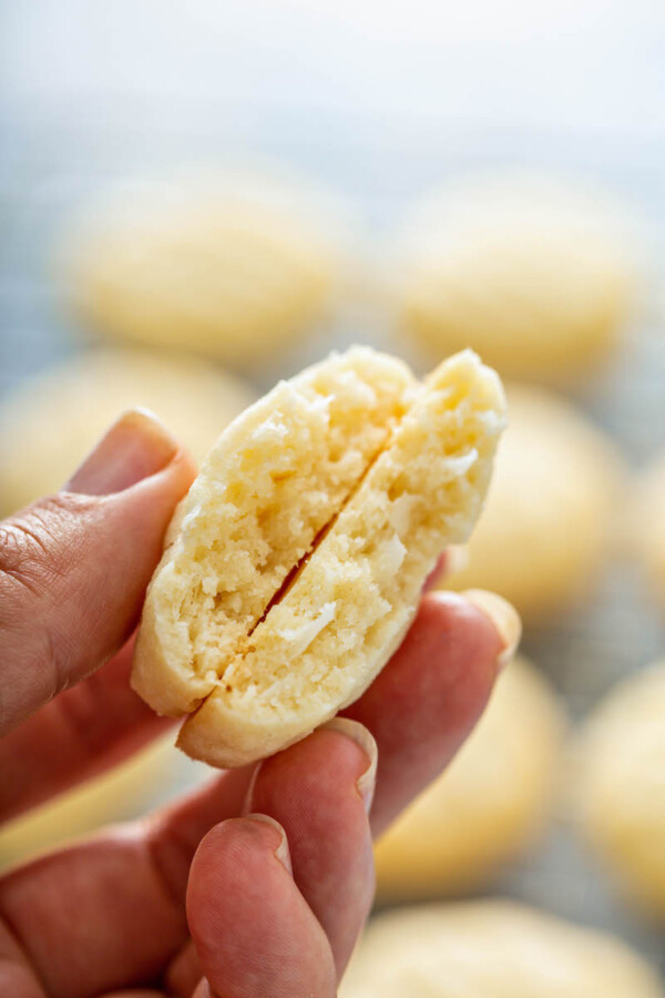 A coconut whipped shortbread cookie has been cut in half, revealing a fully cooked center.