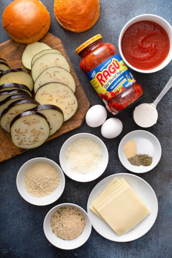 The ingredients for Eggplant Parmesan Sandwiches are placed on a dark surface